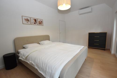 a bedroom with a white bed and a black dresser at Turawski Zakątek in Turawa