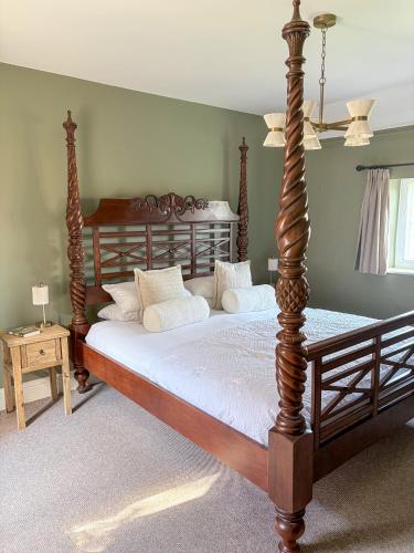 a bedroom with a large wooden bed with white pillows at Castle Cottage Winchcombe in Winchcombe