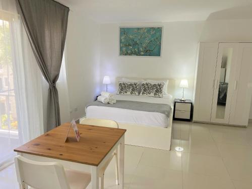 a white bedroom with a bed and a wooden table at CARIBBEAN DREAMS at SOL CARIBE - LOS CORALES beach in Punta Cana