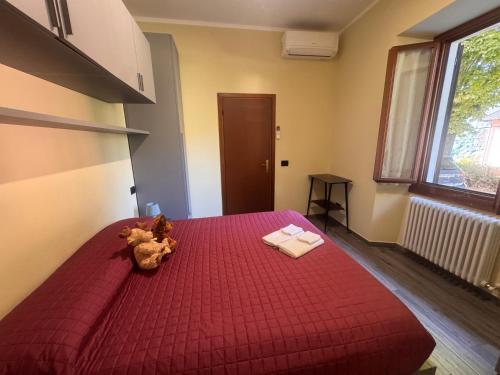 a teddy bear sitting on a red bed in a room at Casa del Cerbiatto, Lake Como a 5 chilometri da Argegno in Castiglione dʼIntelvi