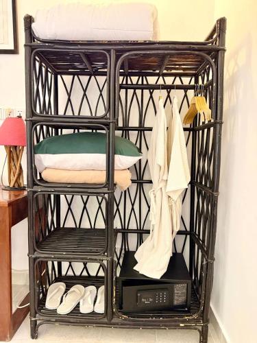 a black iron shelf with a microwave and towels at Au Cabaret Vert in Battambang