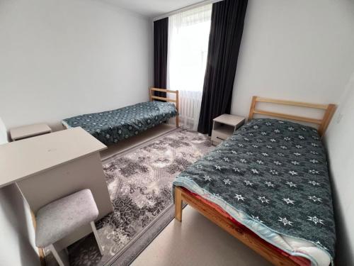 a small room with two beds and a desk at Terme Guesthouse in Naryn