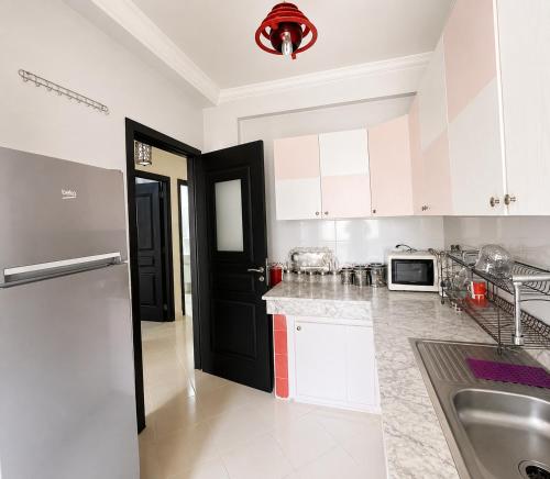 a kitchen with white cabinets and a black door at Stylish and valm appartement in Kenitra