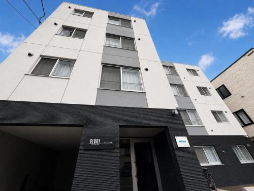 a tall white building with a door in front at Glory 豊平 -FIX HOME- in Sapporo