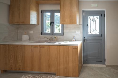 a kitchen with a sink and a window and a door at Zia Village Miro in Lagoúdi Zía