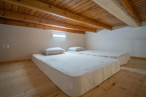 two beds in a room with wooden ceilings at Zia Village Miro in Lagoúdi Zía
