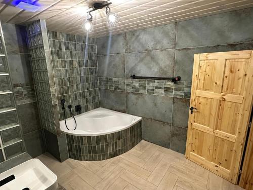 a bathroom with a tub and a sink and a door at Vila Stella Vita in Chrbonín