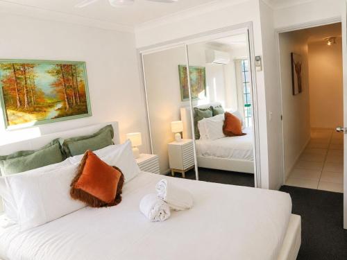 a bedroom with a white bed and a mirror at 2BR Retro Luxe Family Hideaway in Gold Coast