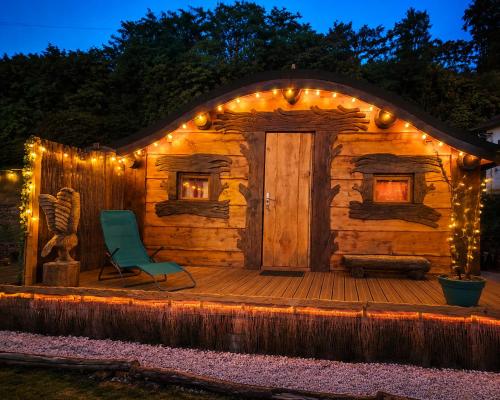 a log cabin with a chair on a deck with lights at Les cabanes féeriques d'Amoncourt in Amoncourt