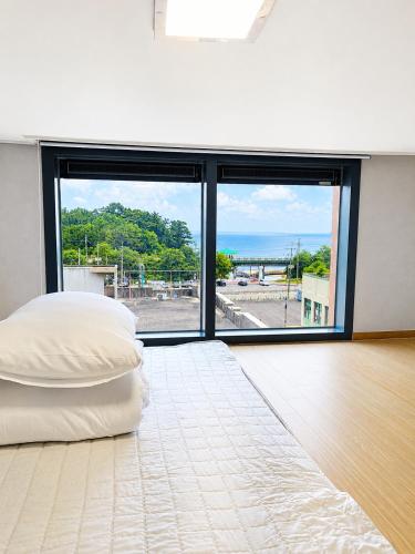 a bedroom with a bed and a large window at Donghae Fine and You Oceancity Hotel by SND in Donghae