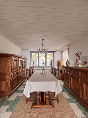 a dining room with a table and chairs and a chandelier at La maison de mamy in Bray-Dunes