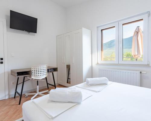 a white bedroom with a desk and a bed at Villa Omaha in Vekići