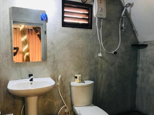 a bathroom with a toilet and a sink and a mirror at Sambu Cabana Panama in Panama