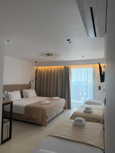 a hotel room with two beds and a window at Alkida Luxury Rooms Tolo in Tolo