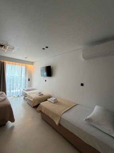 a room with three beds and a flat screen tv at Alkida Luxury Rooms Tolo in Tolo