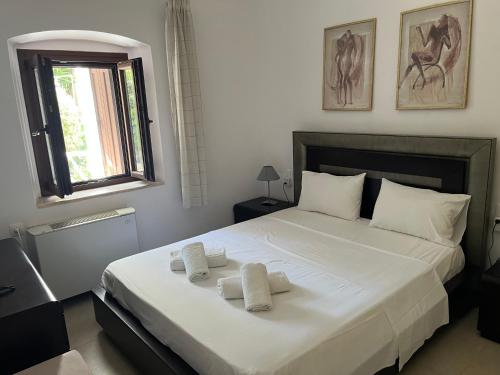 a bedroom with a large white bed with towels on it at Nikotsaras beach house since 1930 in Acharavi