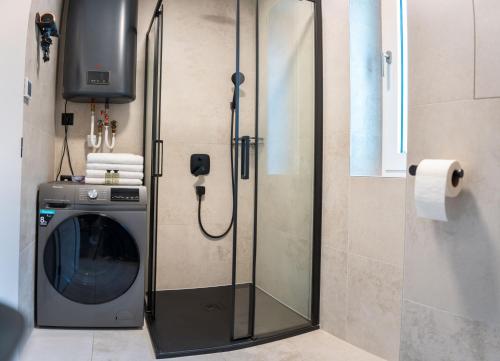 a glass shower door in a bathroom with a washing machine at CASTLE apartments Premium - City Center in Spišské Podhradie