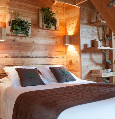 a bedroom with a wooden wall with a bed at Cabane du Bois des Nauzes in Seyches