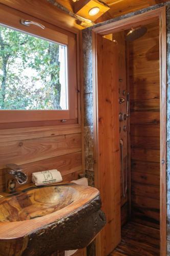 a wooden bathroom with a sink and a window at Cabane du Bois des Nauzes in Seyches