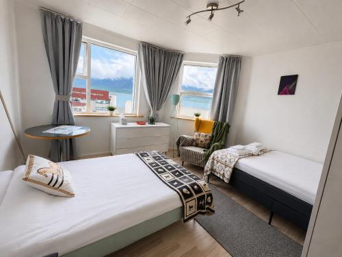 a hotel room with two beds and a chair at Aurora Apartament in Borgarnes