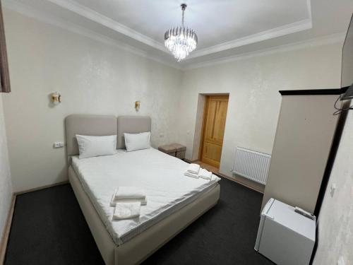 a bedroom with a bed with white sheets and a chandelier at Sobirjon Guest House in Khiva