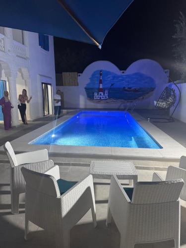 a swimming pool with chairs and a lighthouse in a building at Djerba Moon in Djerba