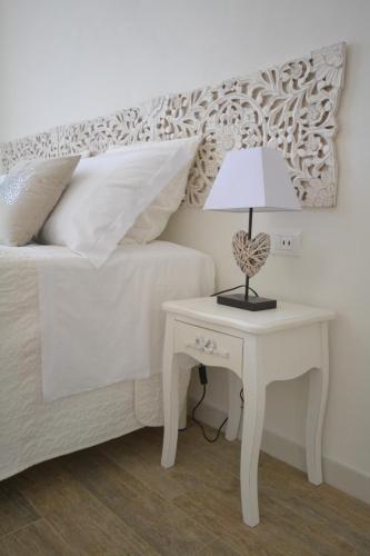 a bed with a white table with a lamp on it at Affittacamere Casa Dane' in La Spezia