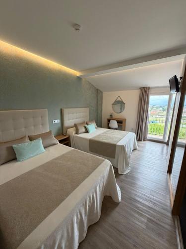 ein Hotelzimmer mit zwei Betten und einem Fenster in der Unterkunft Hotel Marola in A Lanzada