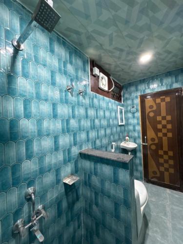 a blue tiled bathroom with a toilet and a sink at Nahor Regency in Guwahati