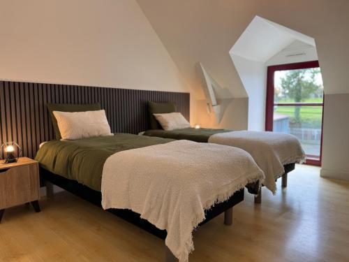 a bedroom with two beds and a window at Gite du haras in Erbrée