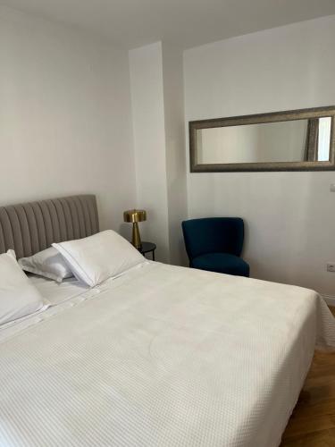 a bedroom with a white bed and a blue chair at Agata in Šibenik