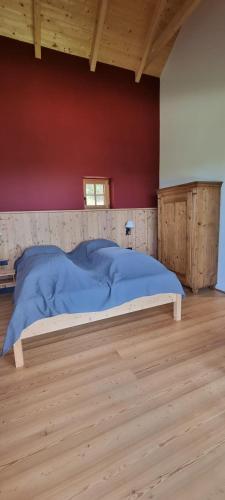 a bed in a room with a red wall at Bergmichlhof in Ragnitz