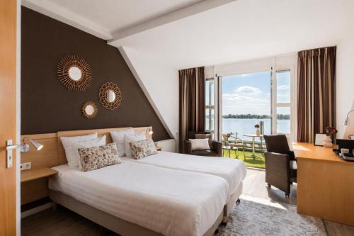 a hotel room with a bed and a desk and a window at Hotel Hoogeerd by Flow Niftrik - Nijmegen in Niftrik