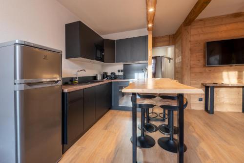 a kitchen with a stainless steel refrigerator and a wooden floor at L'Igloo - Balcon- Vue- Chic pres St-Lary in Vignec