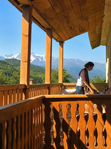 a woman standing on a balcony with a view of mountains at Guest House Keti Margiani Mestia in Mestia