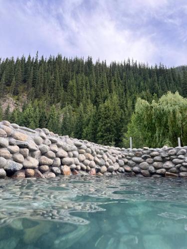 a rock wall next to the water with trees at Darhan Guest House in Darkan