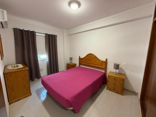 a bedroom with a bed with a pink blanket at Casa Caravela C in Armação de Pêra