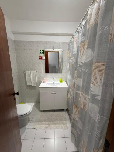 a bathroom with a sink and a toilet and a mirror at Casa Caravela C in Armação de Pêra