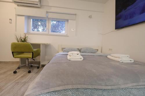 a bedroom with a large bed and a green chair at Cozy Studio in Downtown Sesvete in Sesvete