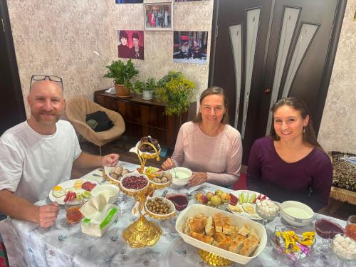 a group of people sitting at a table with food at Asylbek Guesthouse horseback riding tours in Kyzart