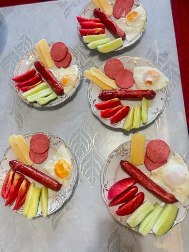 a table topped with plates of food with sausage and vegetables at Asylbek Guesthouse horseback riding tours in Kyzart