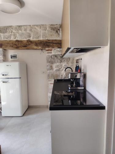 a kitchen with a black counter top and a refrigerator at VODIČARJEVA HiŠiCA in Grgar