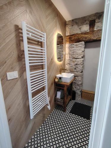 a bathroom with a sink and a stone wall at VODIČARJEVA HiŠiCA in Grgar