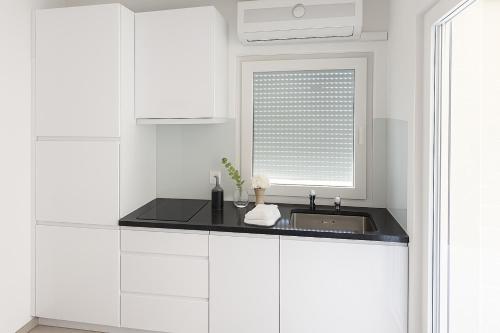 a white kitchen with a sink and a window at Aksa Residences in Vir