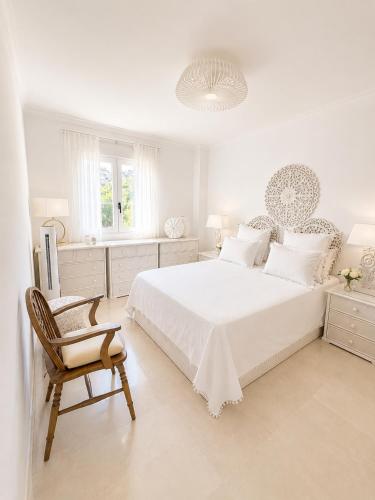 a white bedroom with a white bed and a chair at Beach Penthouse Apartment in Jávea