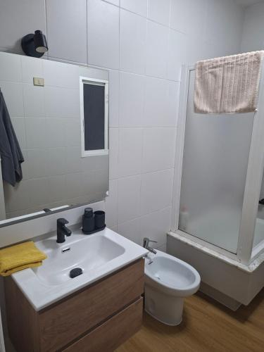 a bathroom with a sink and a toilet and a mirror at Piso 4 dormitorios playa sada in Sada