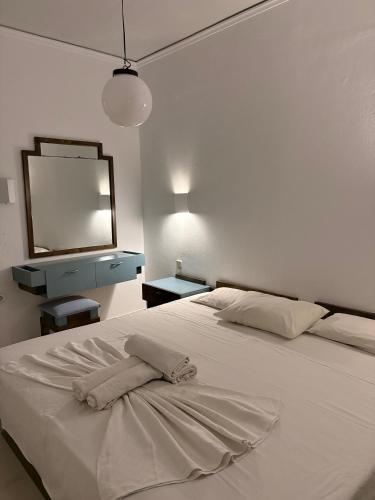 a bedroom with a large white bed with a mirror at Skala Apartments in Agia Marina Nea Kydonias