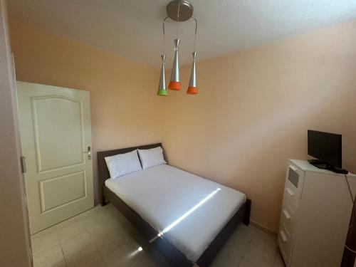 a small bedroom with a white bed and a television at MELIA Holidays & Living in Epanomi