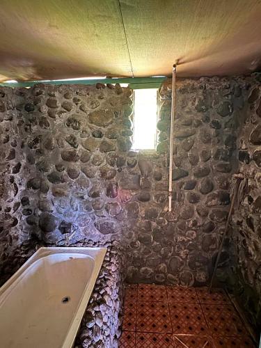 ein Badezimmer mit Badewanne und Steinwand in der Unterkunft Niusiladi in Taveuni