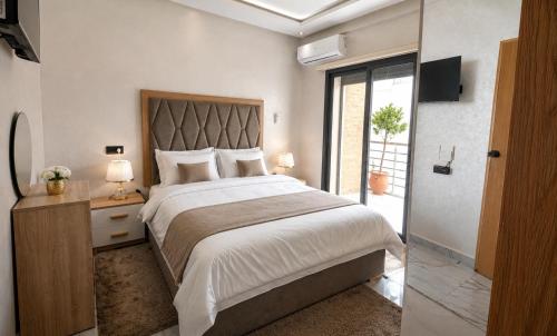 a bedroom with a large bed and a sliding glass door at AL MIDYAF Appart'Hôtel in El Jadida